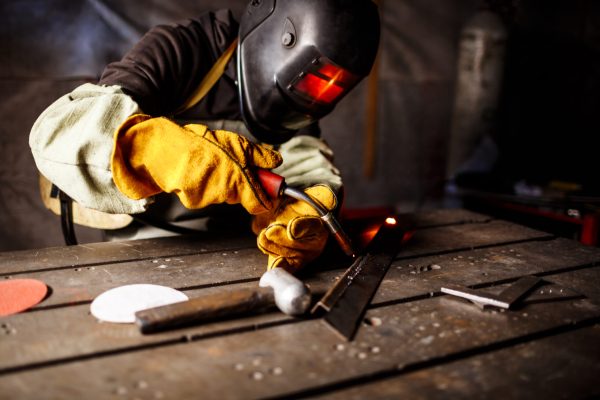 Worker cutting metal with plasma equipment on plant.