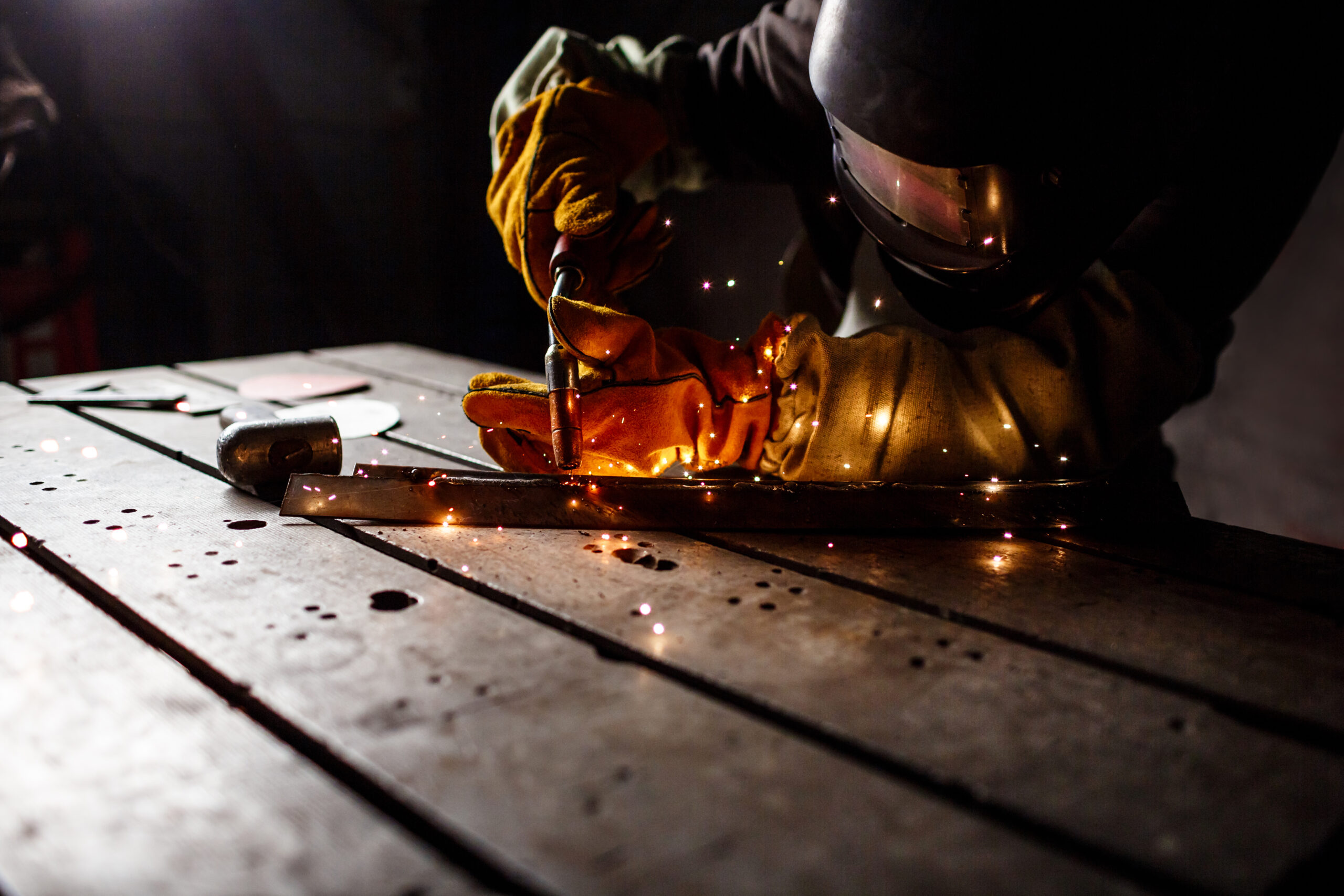 Worker cutting metal with plasma equipment on plant.
