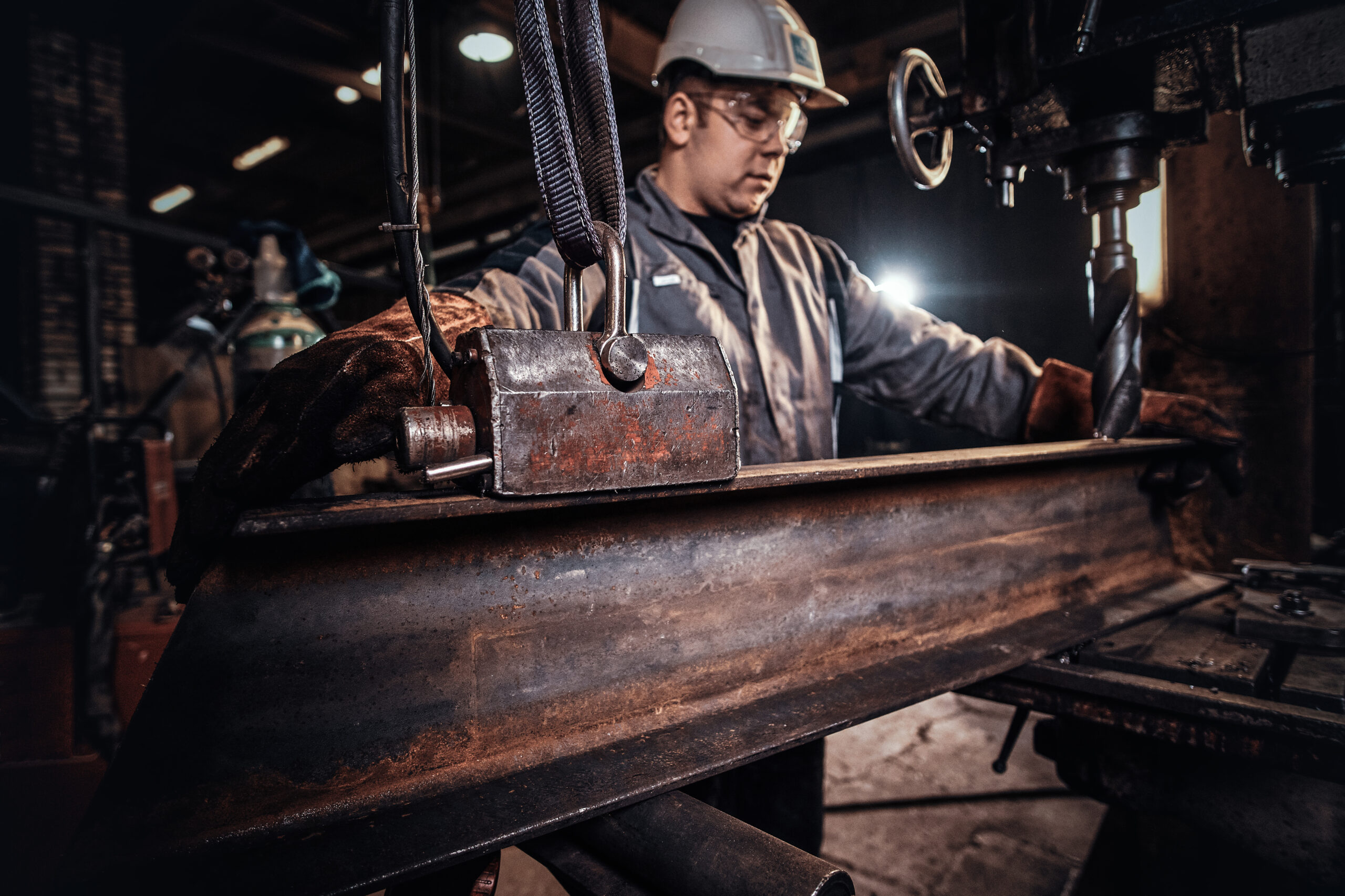 Man in helmet is moving a piece of rail at metal factory.