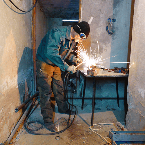 Welder working at a table in a small workshop