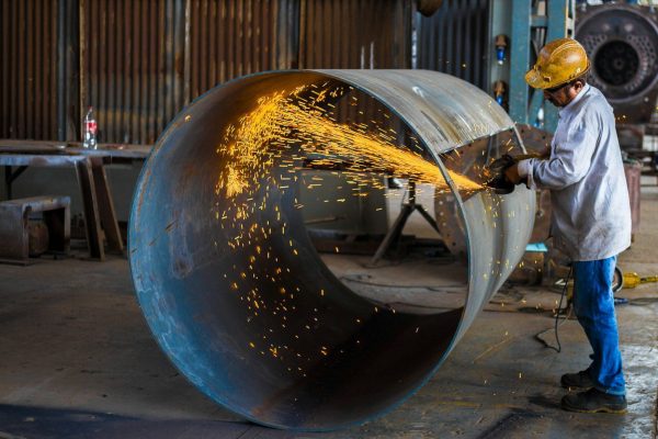 Worker grinding a large metal pipe