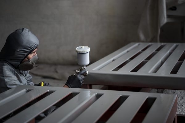 Worker spray painting a metal frame
